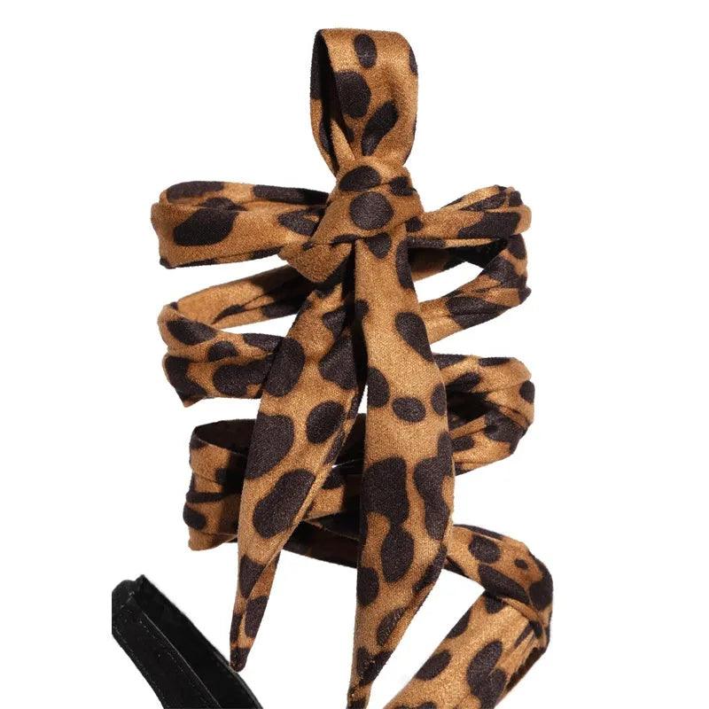 Light brown leopard print women's high heel sandals with Roman style cross straps and a thin high heel.