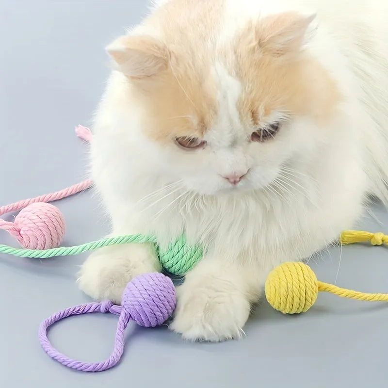 Green cat toy ball with attached rope and internal bell next to a pink one.