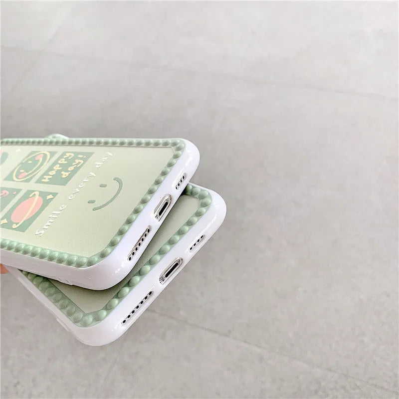Green flexible TPU iPhone case with a geometric smiley face and polka dot frame design on the back.