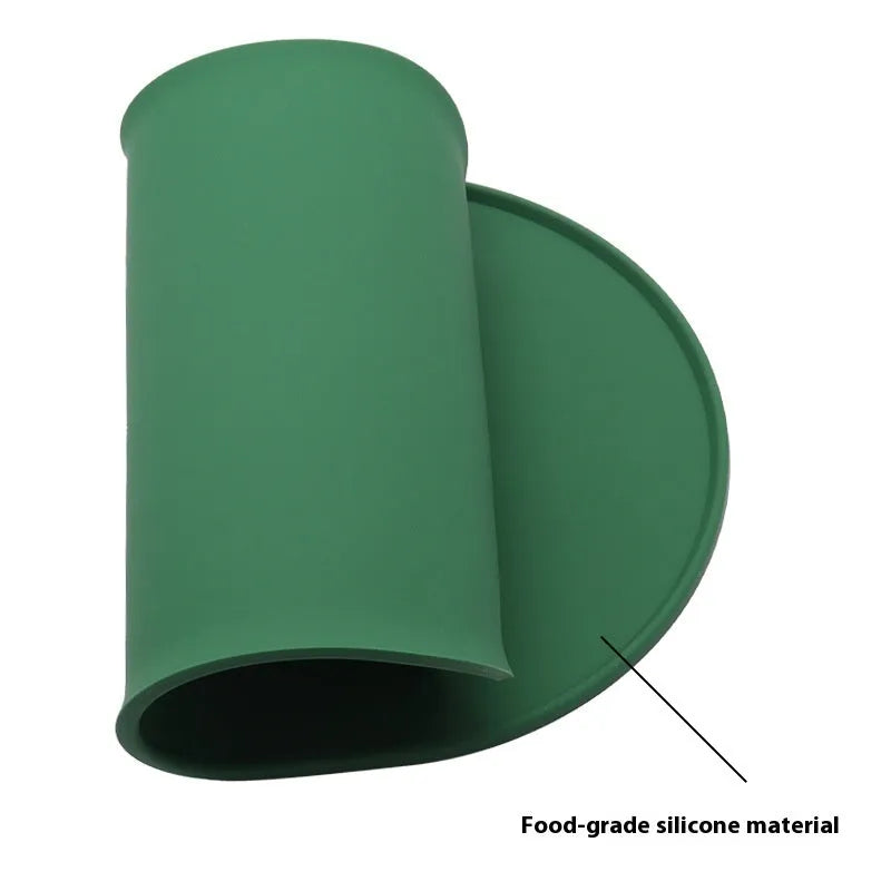 A green silicone placemat for cat food and water bowls on a wooden floor.
