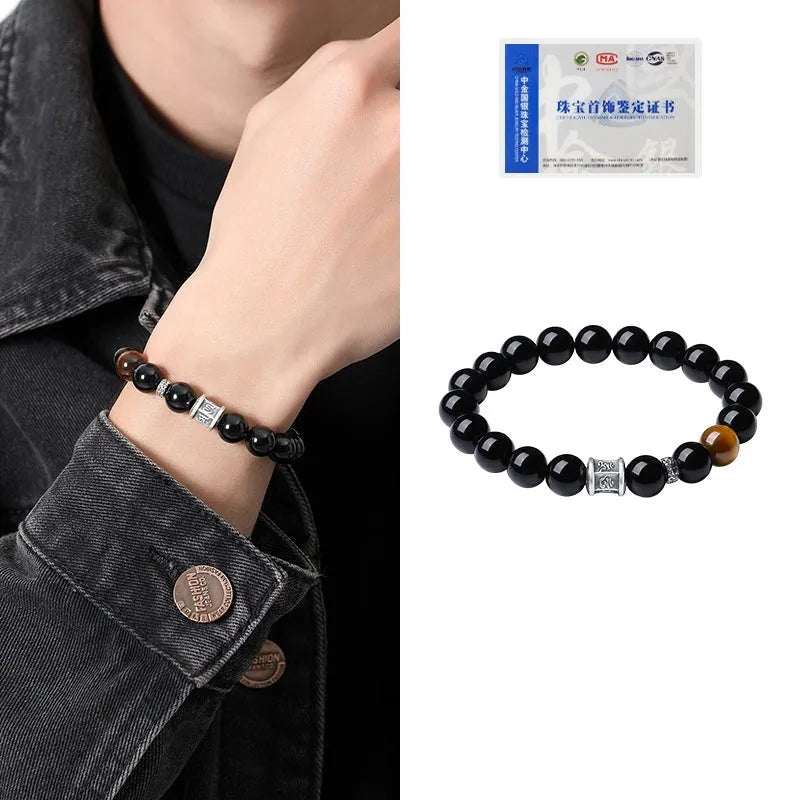 Mens black obsidian bracelet with silver prayer wheel charm on wrist