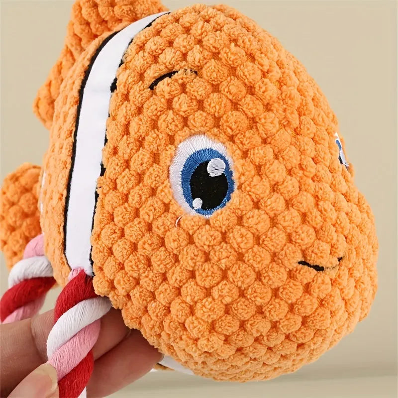 Grey turtle-shaped plush dog toy with four knotted rope legs on a wooden floor.