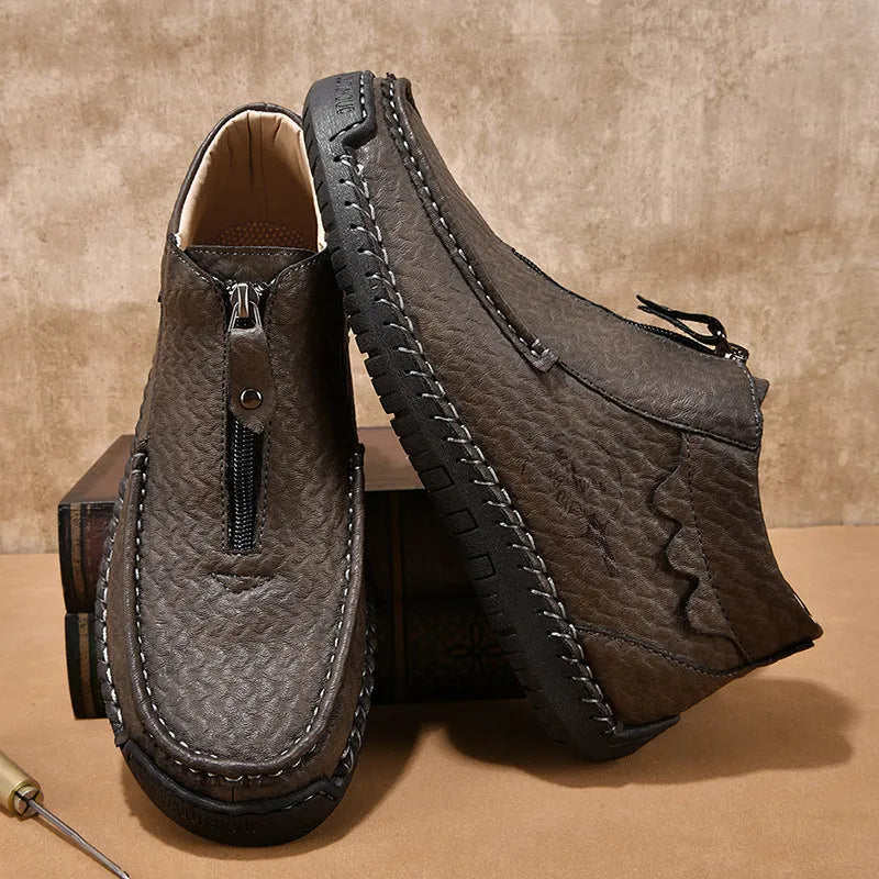 Men's black slip-on leather loafers with round toe and rubber sole, shown in a casual setting.