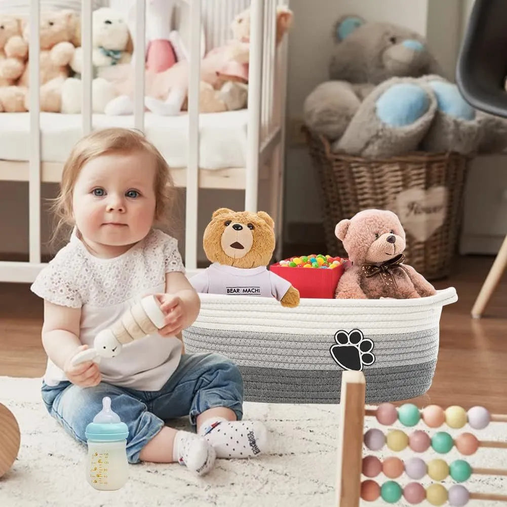 Handmade light beige woven cotton rope storage basket with a handle, shown on a wooden surface.