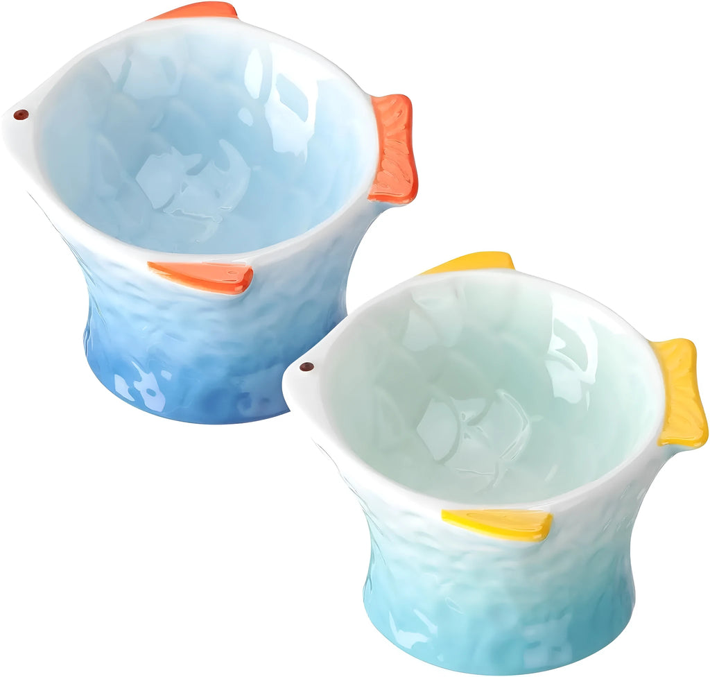 Blue fish-shaped ceramic cat bowl with tilted angle and elevated base on a table.