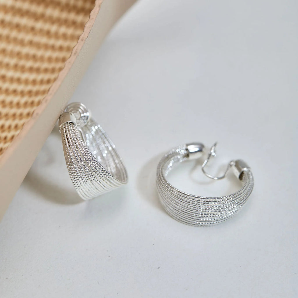 Set of geometric multi-layer earrings in gold and silver, showing stud and clip styles on a flat surface.