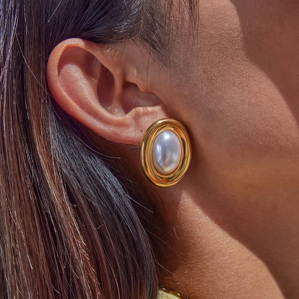 A pair of gold-colour stainless steel ear studs with a vintage pearl centre and butterfly clutch backs.