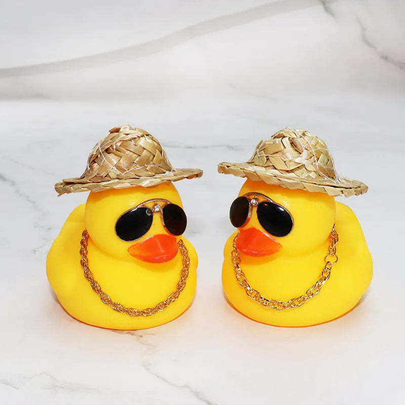 Yellow cartoon duck car ornament wearing a straw hat, with miniature sunglasses accessory.