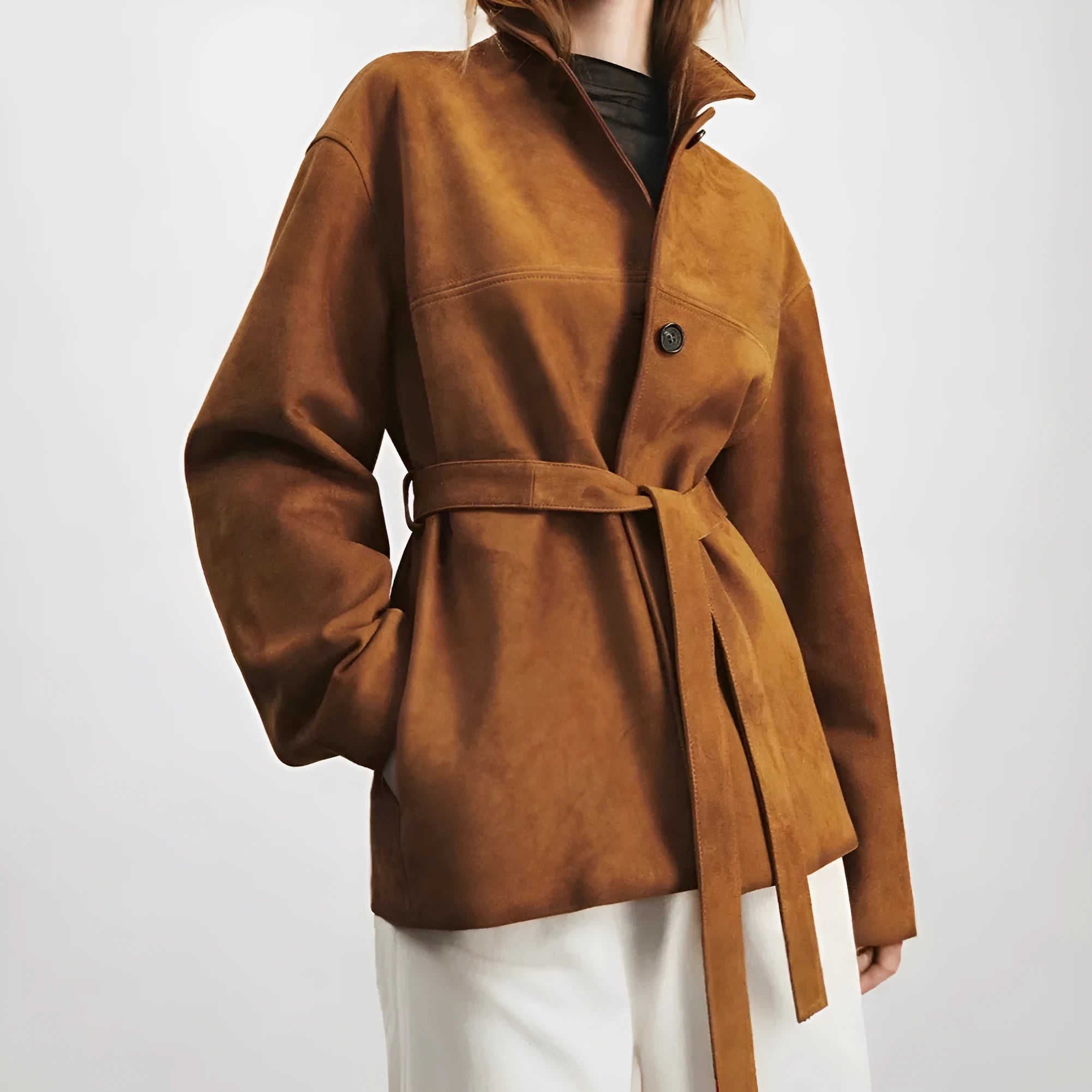 Yellow brown retro cashmere coat with Peter Pan collar, leather stitching, and a belt on a hanger.
