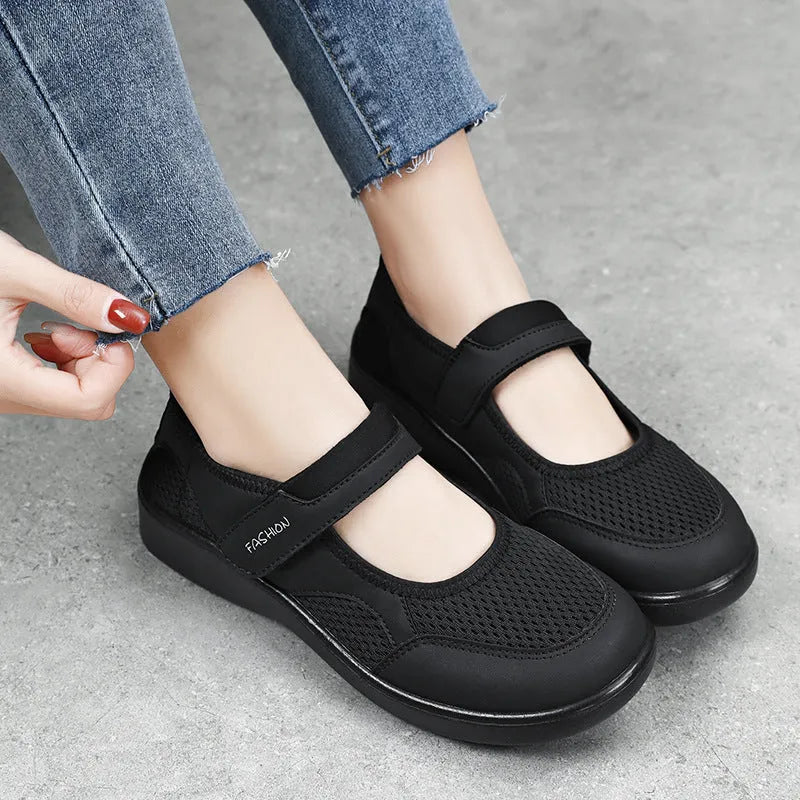 Women's grey breathable mesh slip-on shoe with Velcro strap, flat heel, and round toe.