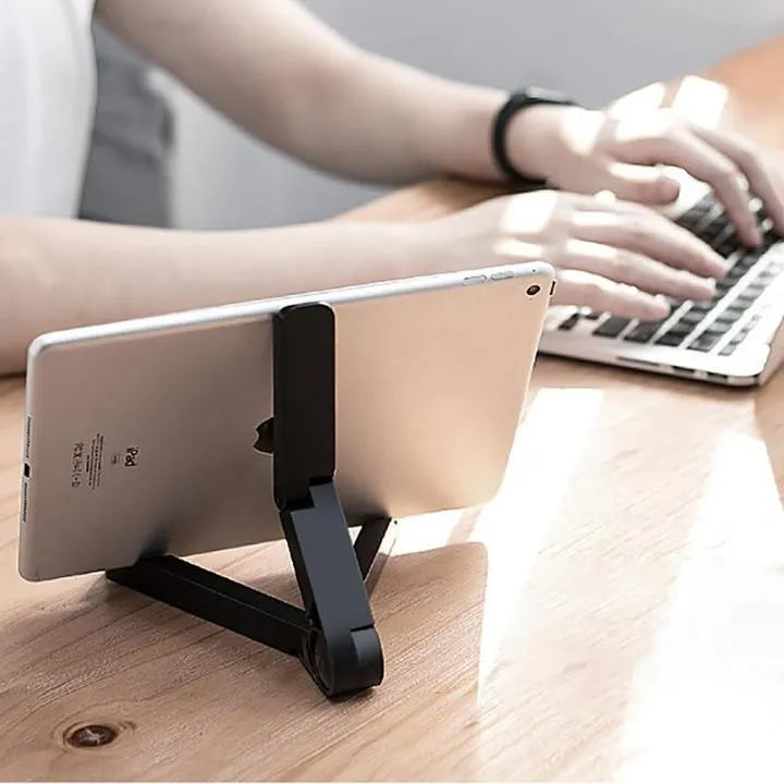 Black foldable tablet holder open in landscape mode holding a smartphone, showing its compact size and non-slip rubber surface.