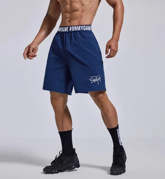 Man wearing loose black sports shorts with letter print detail, showing elastic waist and cropped length.