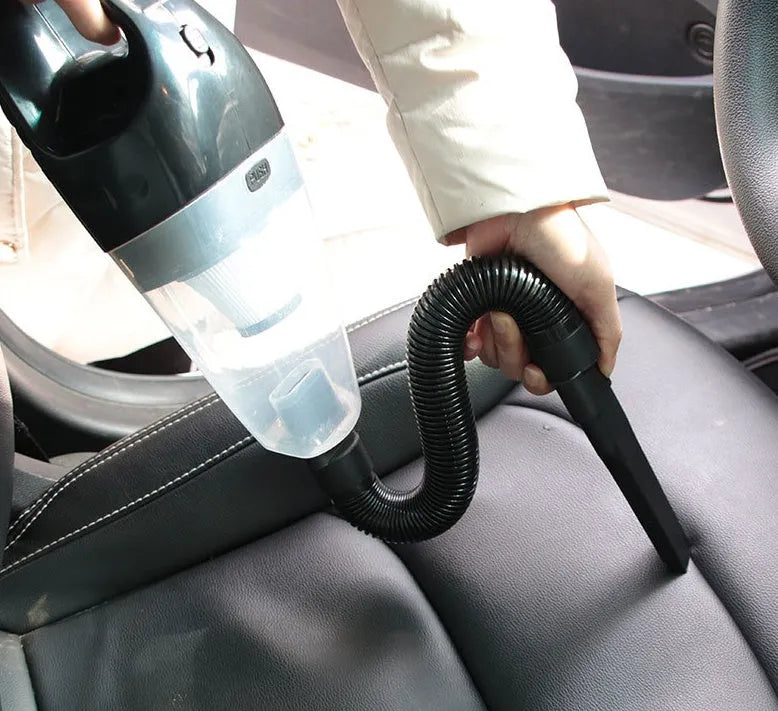 Orange and black handheld car vacuum cleaner with hose, nozzles, and a long power cord with cigarette lighter plug.