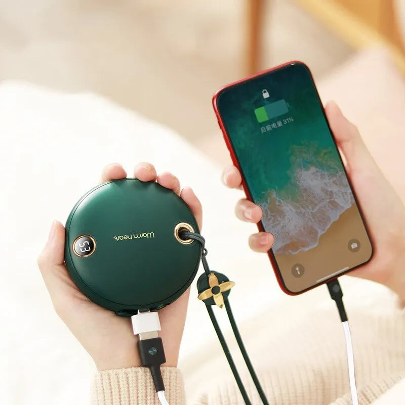 Green hand warmer power bank with digital display showing battery percentage, next to a charging cable.