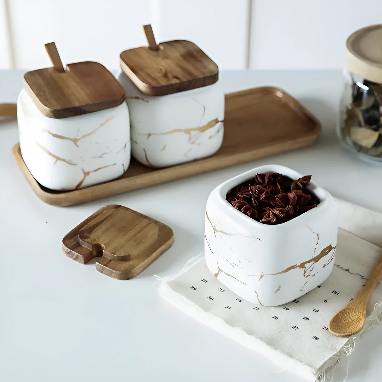 Nordic gold marble ceramic jar set with wooden tray and bamboo spoon on a kitchen counter