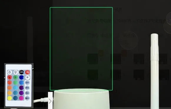 3D acrylic LED message board night light with remote control and marker pen on a desk.