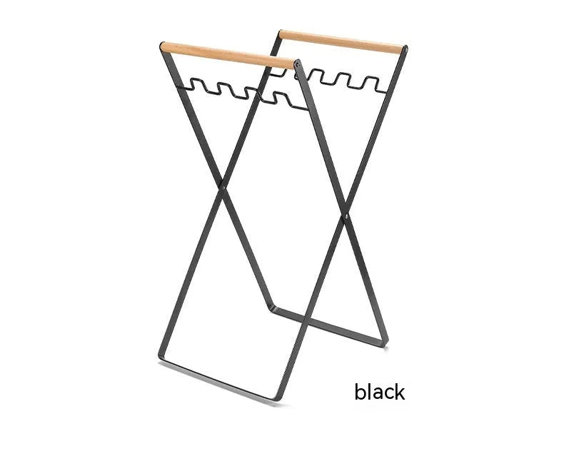Black outdoor folding trash rack with wooden handle holding a white bin bag open.