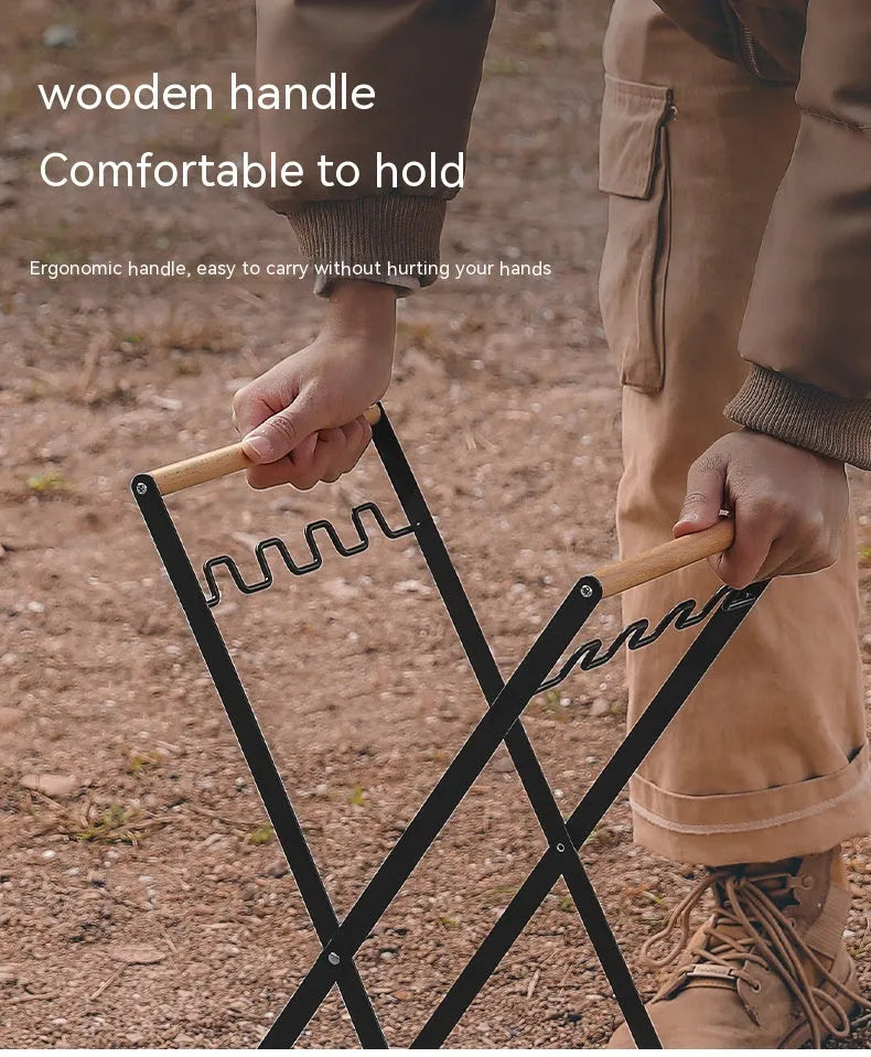 Black outdoor folding trash rack with wooden handle holding a white bin bag open.