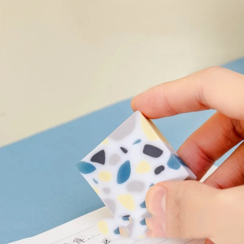 A rectangular brick-shaped white rubber eraser for removing pencil marks.