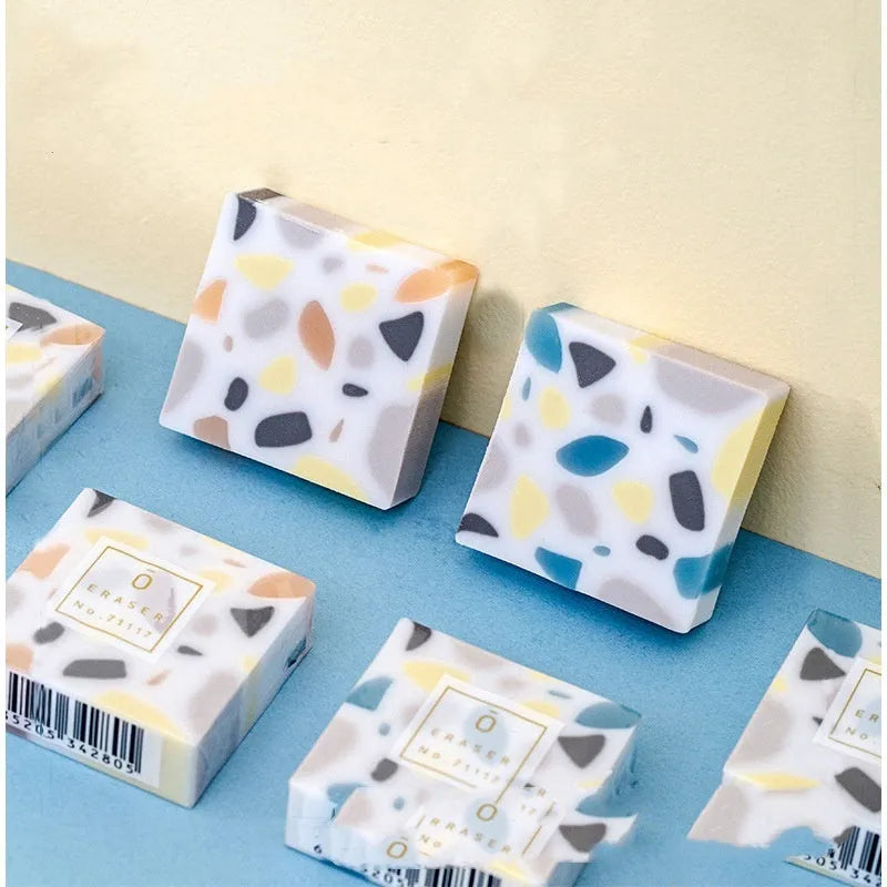 A rectangular brick-shaped white rubber eraser for removing pencil marks.