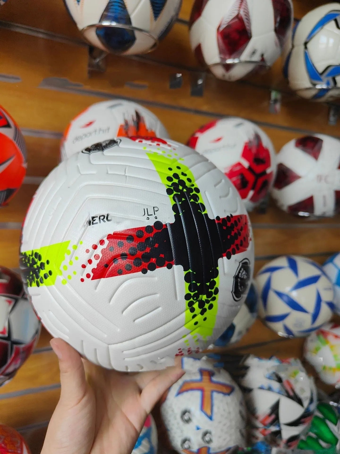 Fluorescent green size 5 PU football with seamless thermal adhesive construction on a pitch.