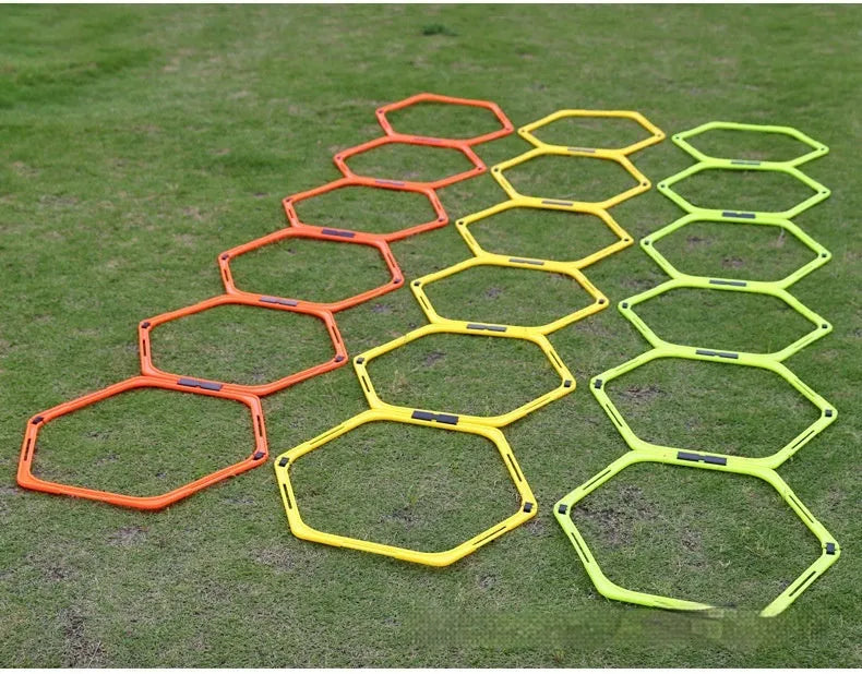 Set of six foldable yellow, green, and orange hexagon agility training rings on grass.