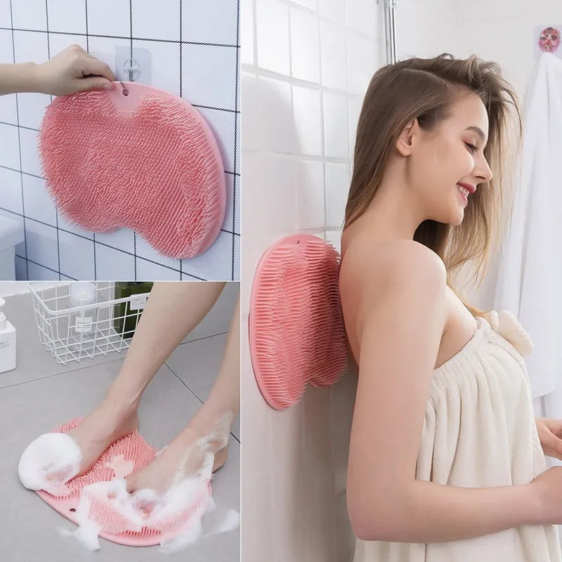 Orange non-slip massage bath brush with suction cups and soft silicone bristles on a bathroom floor.
