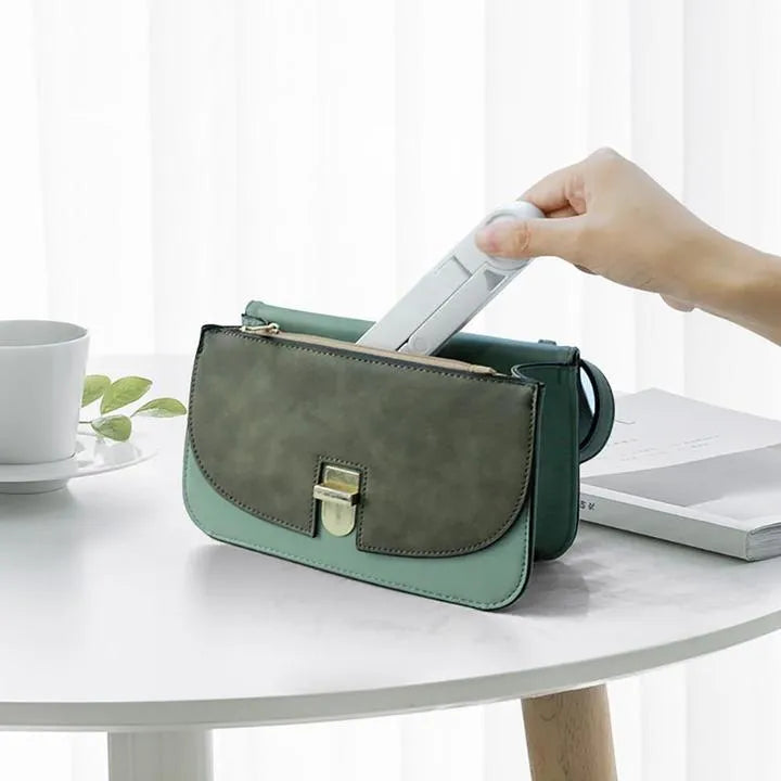 Black foldable tablet holder open in landscape mode holding a smartphone, showing its compact size and non-slip rubber surface.