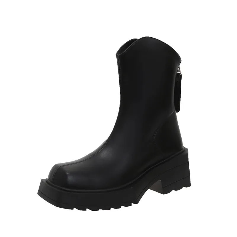 Black platform Martin ankle boots with a square toe, chunky heel, and back zipper on a woman's feet.