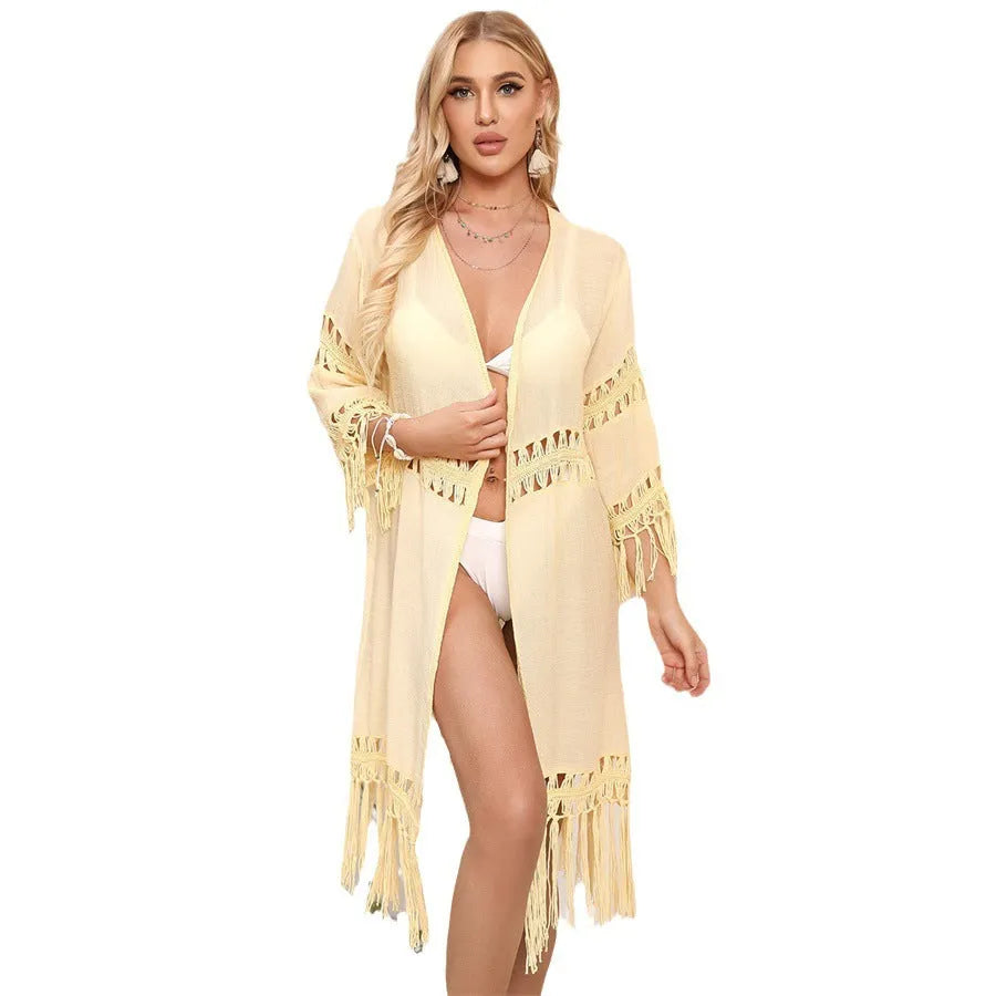 Hand-crocheted yellow acrylic beach cover-up cardigan with loose stitches and tassel trim on a mannequin.