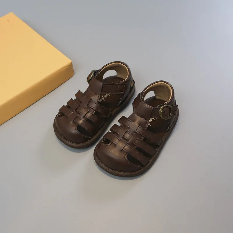 Girls' closed toe PU leather woven hollowed Roman sandals with Velcro strap, beige colour, on toddler feet