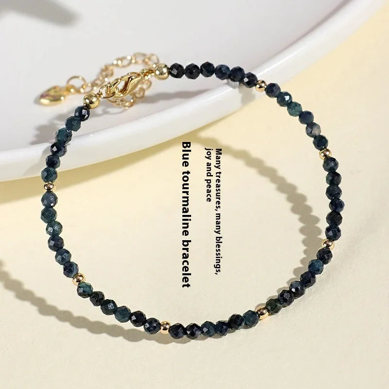 Close-up of a 3mm blue tourmaline cut bead spacer bracelet on a wrist.