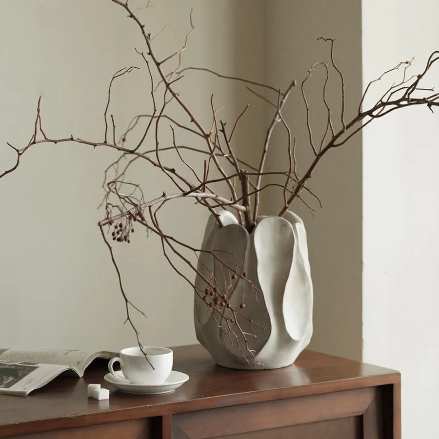 Irregularly shaped art ceramic vase in a low style profile on a wooden surface