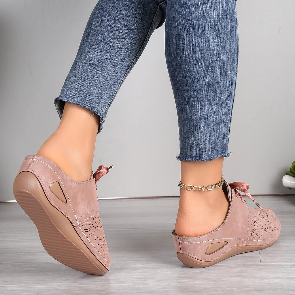 Women's lace-up suede wedge slippers with a hollow-out design, shown in a light colour on a foot.