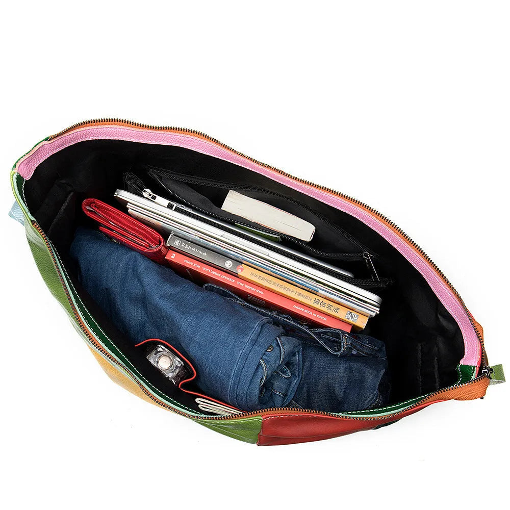 Brown cowhide leather crossbody travel bag with stitching details, shown next to a laptop and magazine.