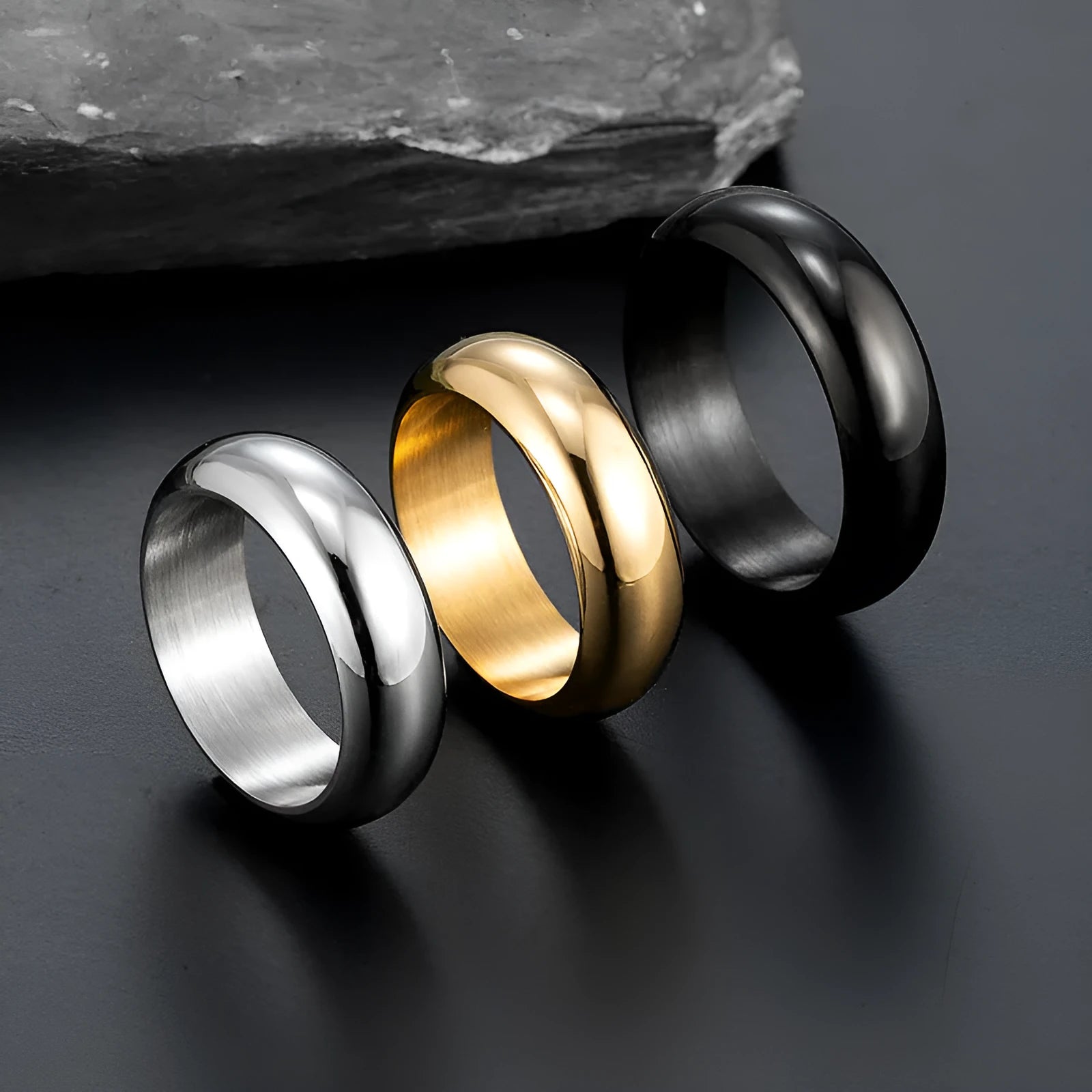 Glossy electroplated titanium steel ring in gold, black, and steel colours on a jewellery background.