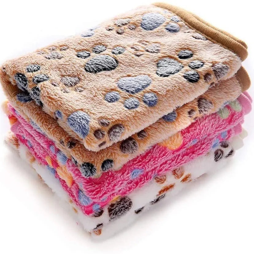 Coral fleece dog blanket with paw print pattern in beige, shown on a dog bed.
