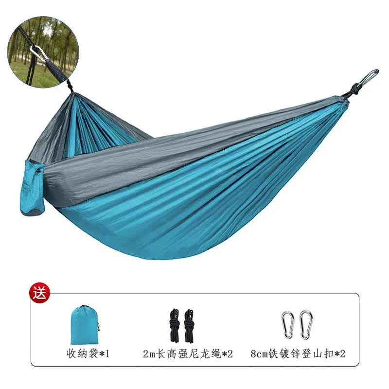 Blue nylon camping hammock hanging between trees with parachute fabric construction