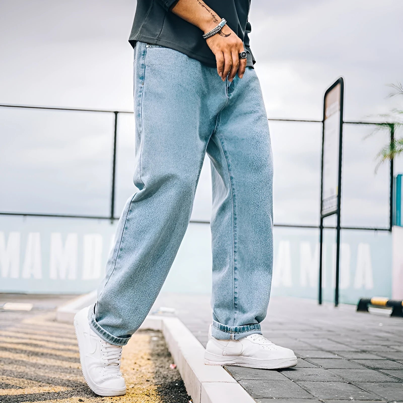 Men's loose straight-cut cotton jeans in dark blue, shown on a man in a casual setting.