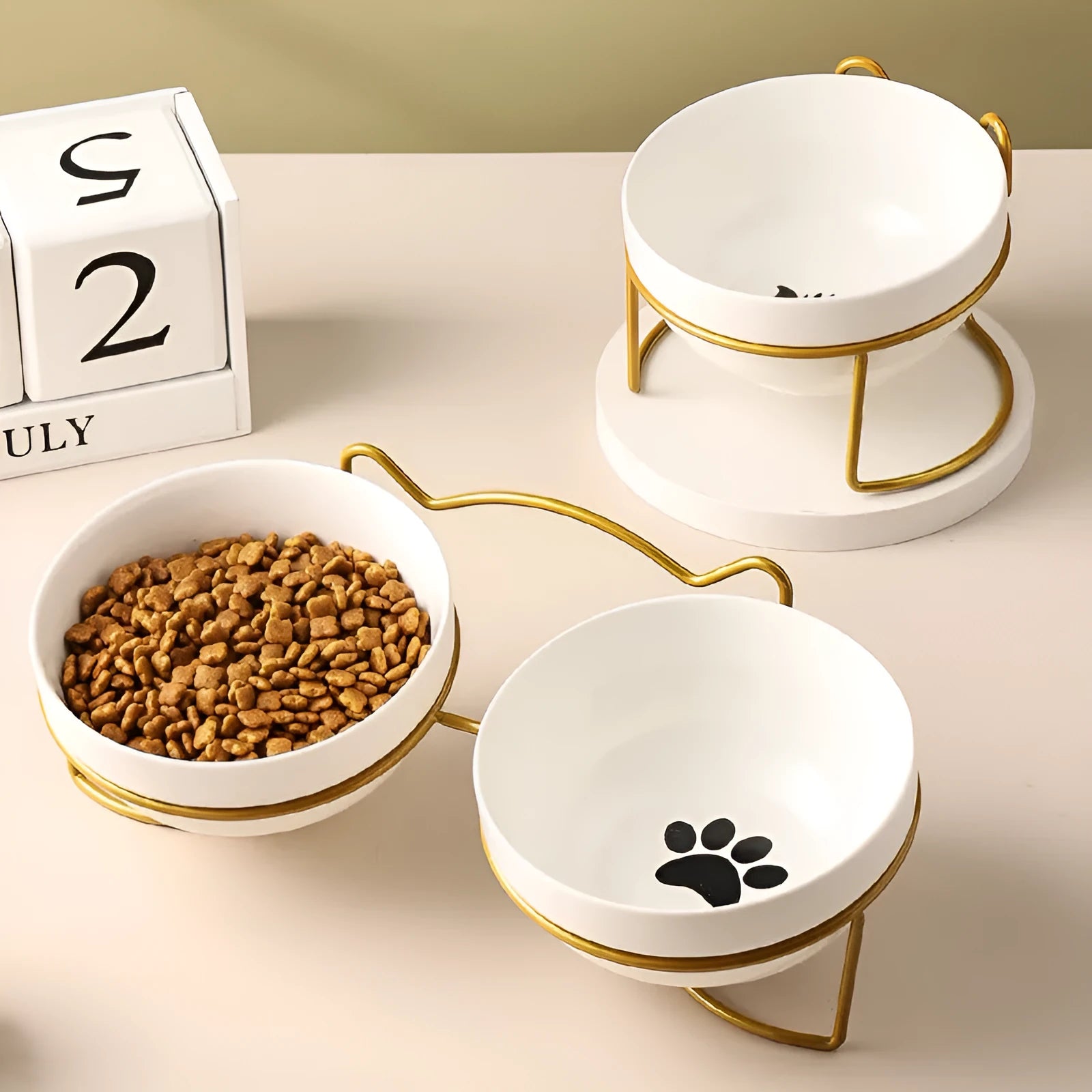 White ceramic cat bowl with paw print design in a black iron cat-ear frame.