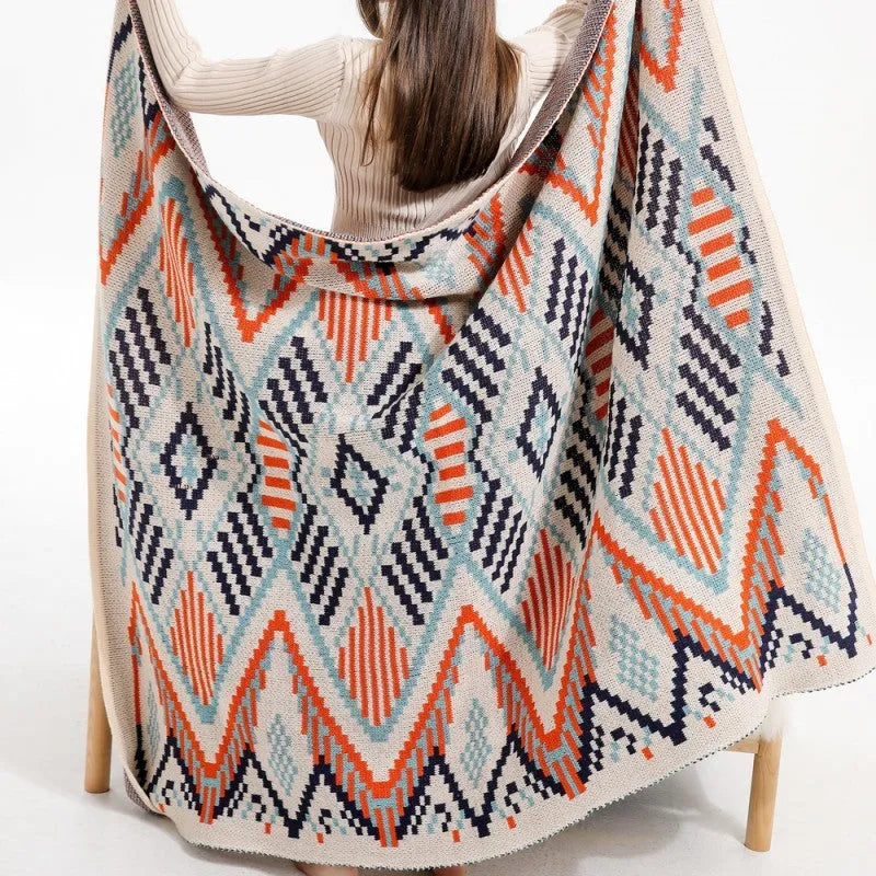 Bohemian-style acrylic sofa blanket with tassel trim shown in a beige and orange colour.