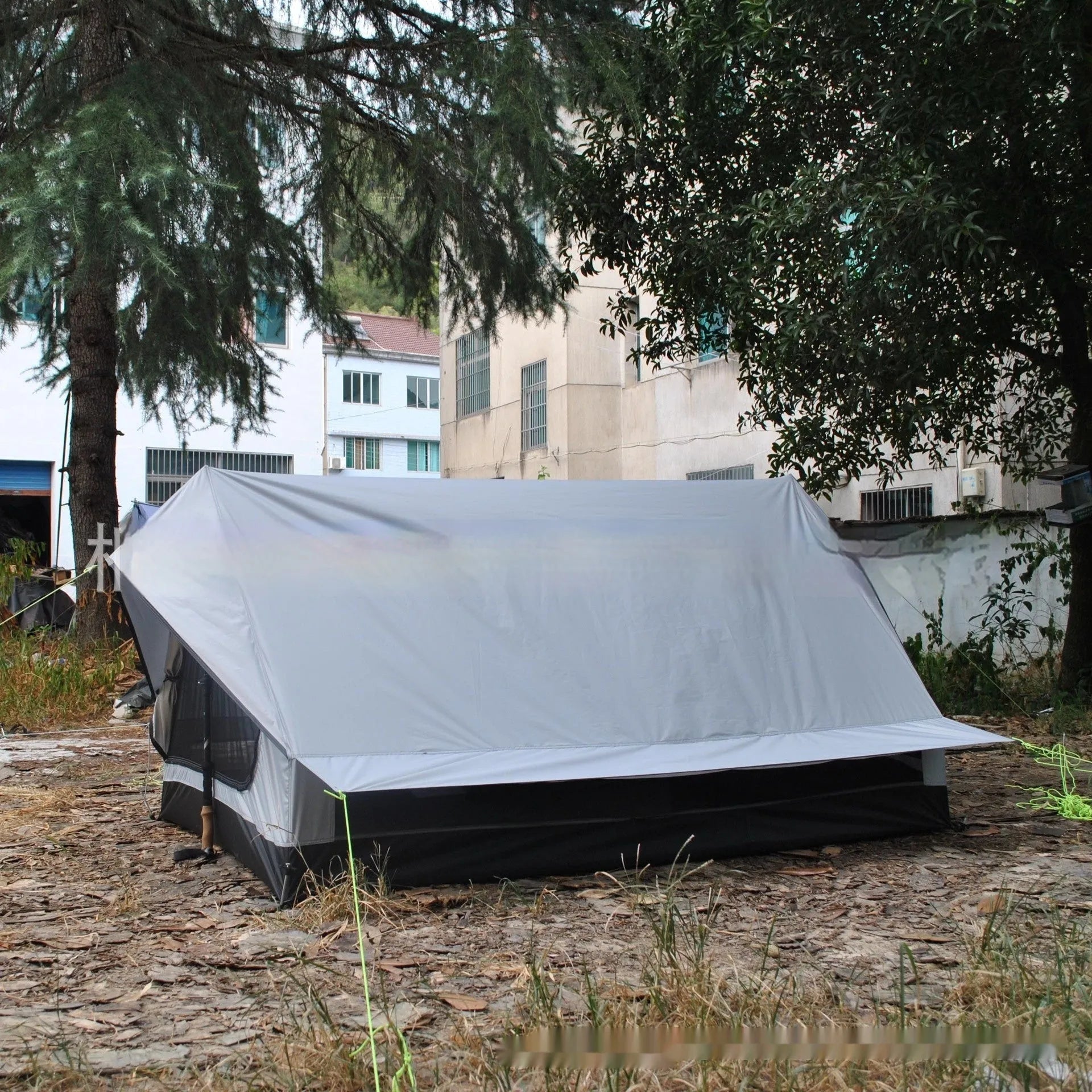 Brown A-line cabin tent pitched using hiking poles with aluminium ground nails and fluorescent wind ropes