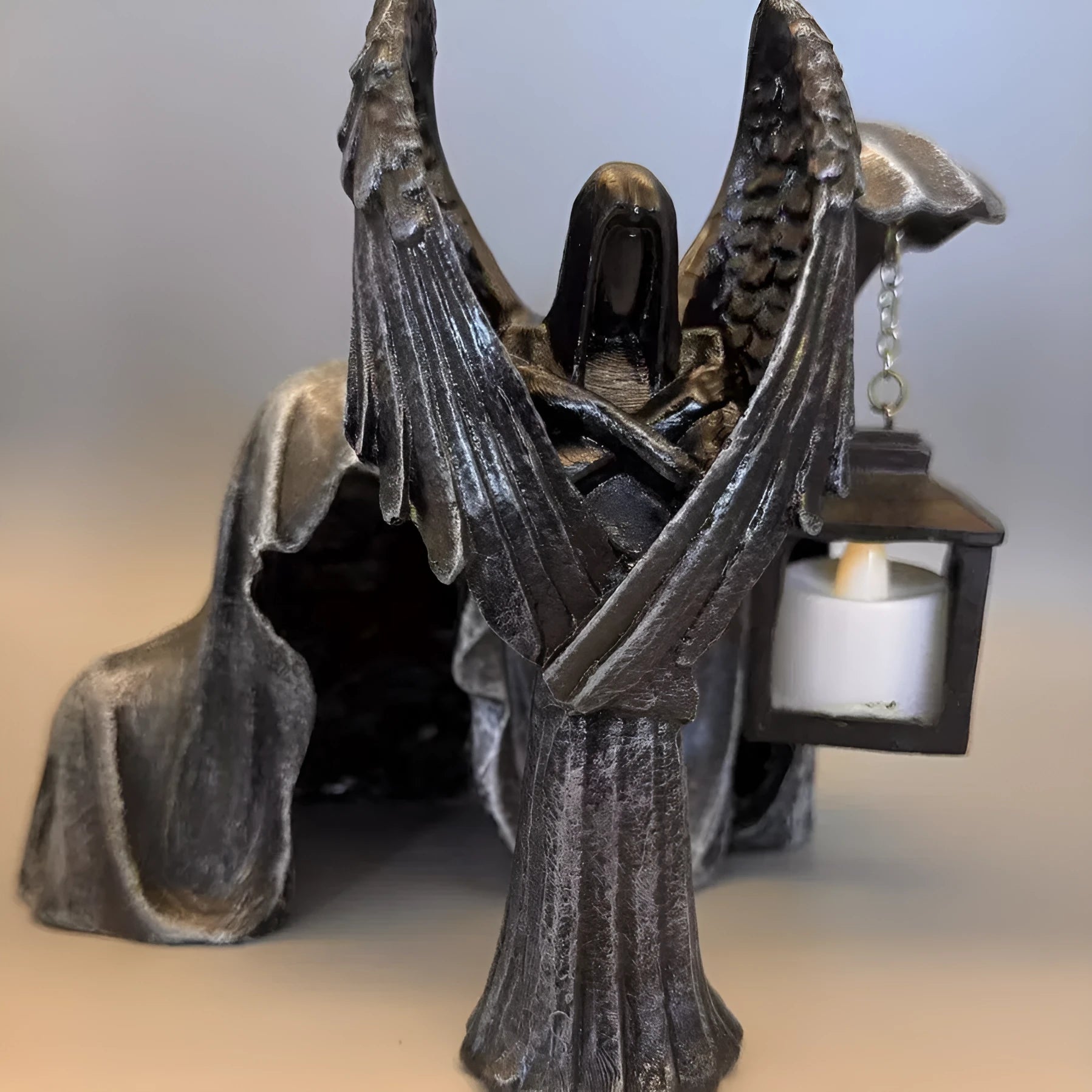 Small dark angel resin statue ornament on a table, showing detailed wings and robe.