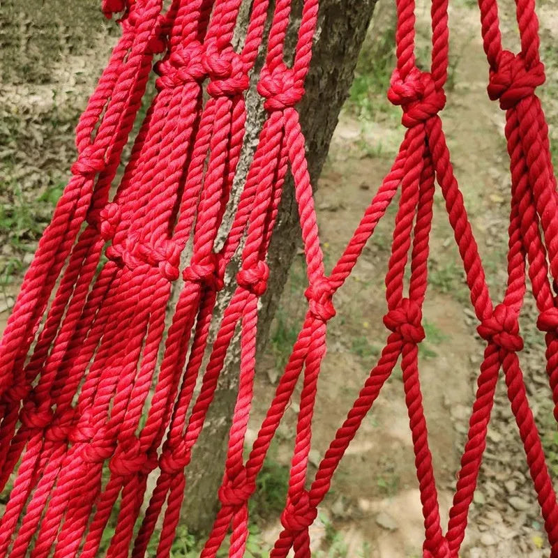 Bold style outdoor nylon rope mesh hammock hung between two trees.
