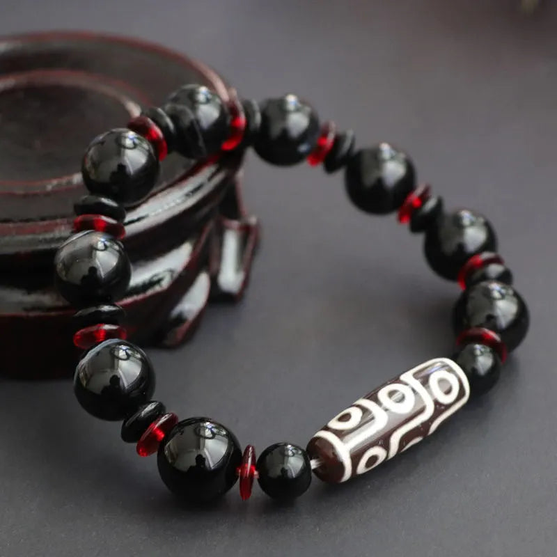 Close-up of a hand-woven black agate dzi bead bracelet with 11mm geometric beads on a wrist.