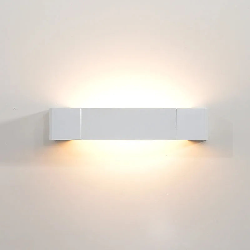 Modern minimalist wall lamp with aluminium shade in gold finish against a white wall