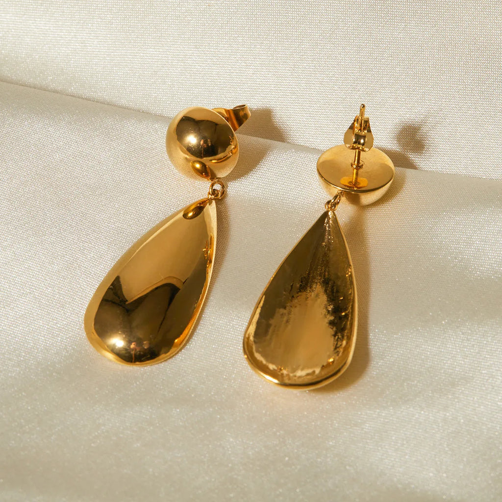 A pair of gold-coloured stainless steel earrings featuring geometric hemisphere shapes forming a water droplet design.