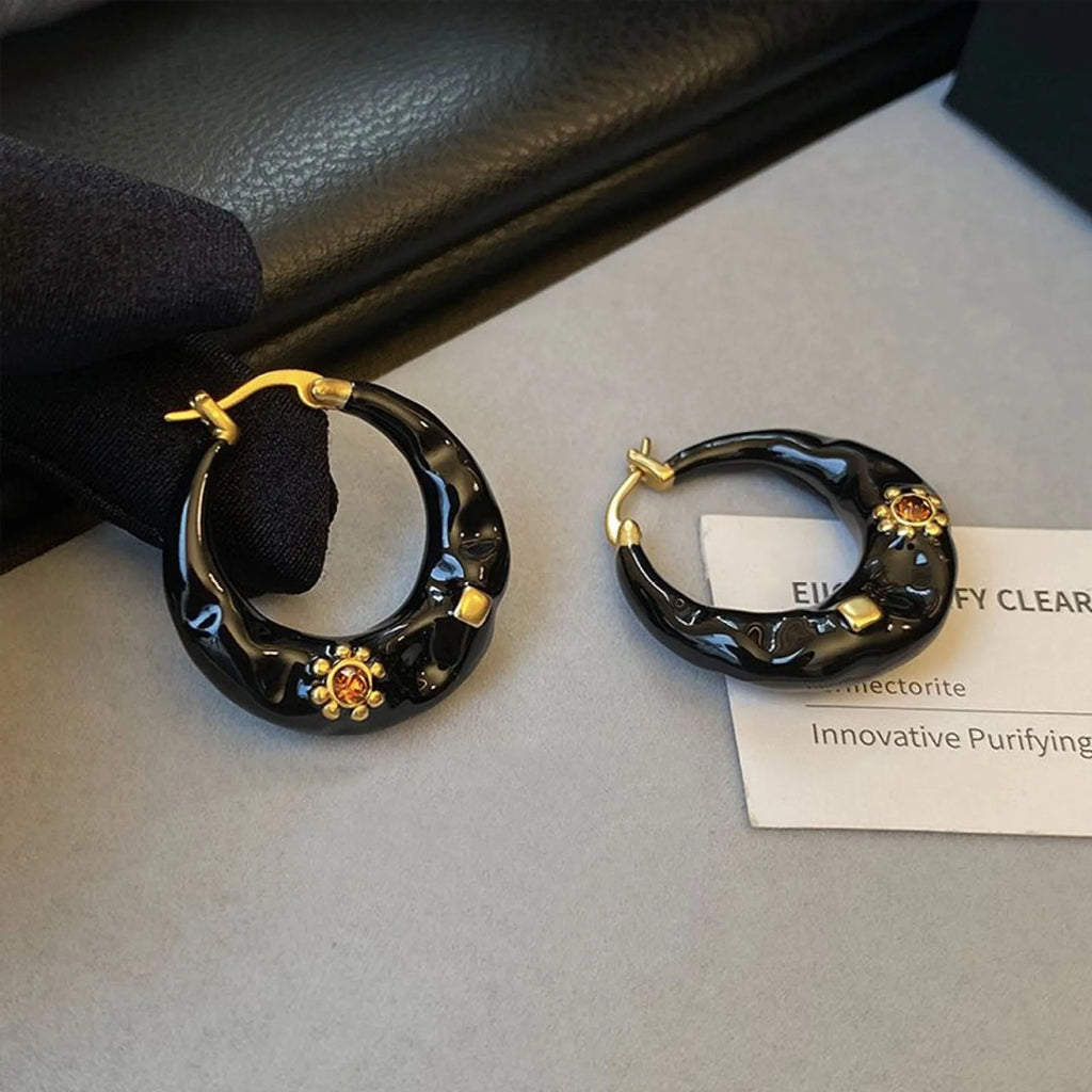 A pair of retro alloy ear studs with a dripping oil finish and black rhinestone detail.