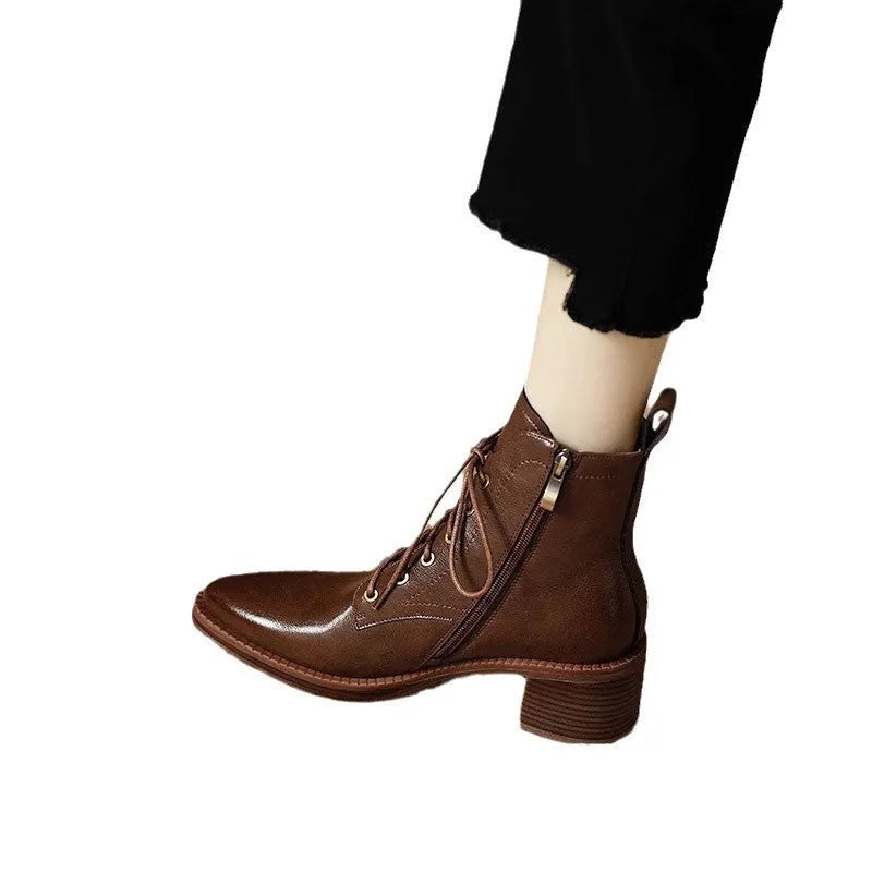 Women's black pointed-toe short tube ankle boots with a low block heel on a neutral background.