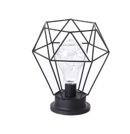 Hollow wrought iron wine bottle shaped table lamp with warm white LED light on a wooden desk